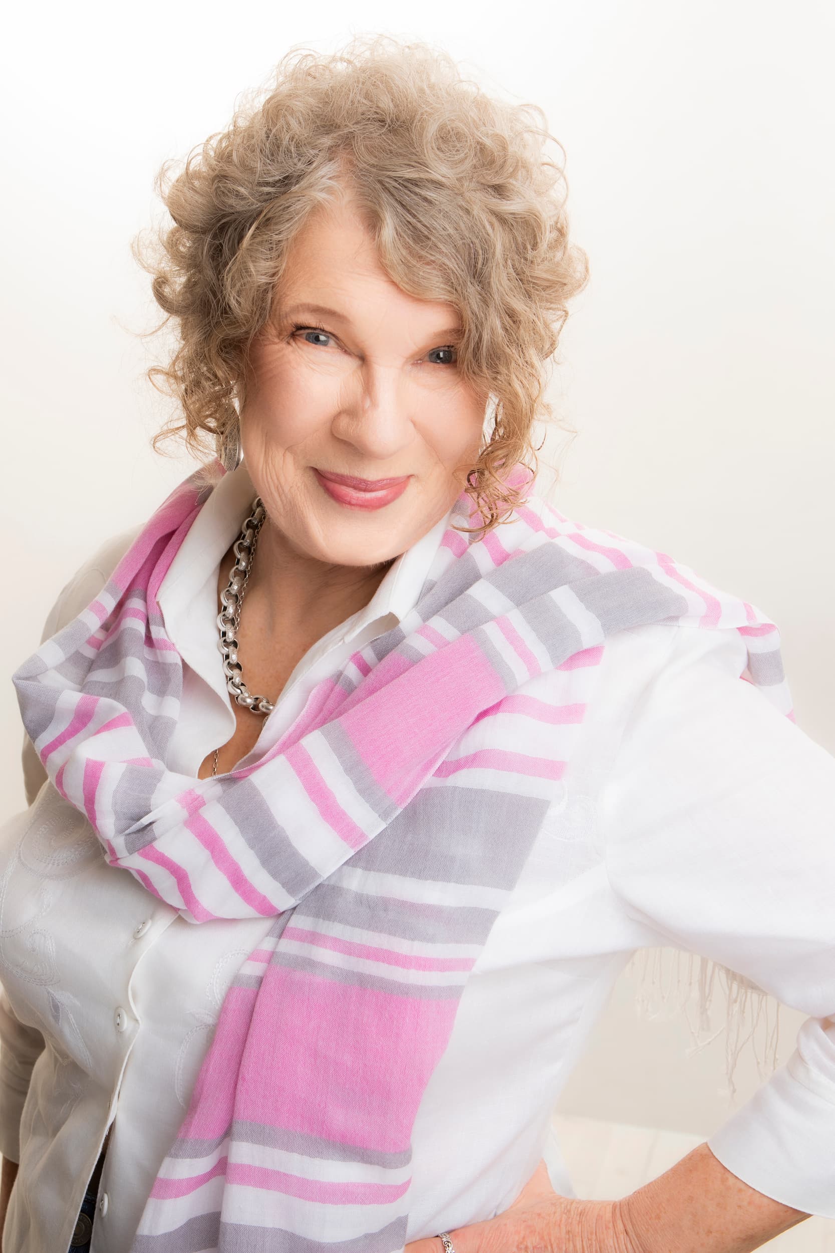 Professional portrait of Narelle Blakeman from Positive Health smiling in a white blouse and pink striped scarf.