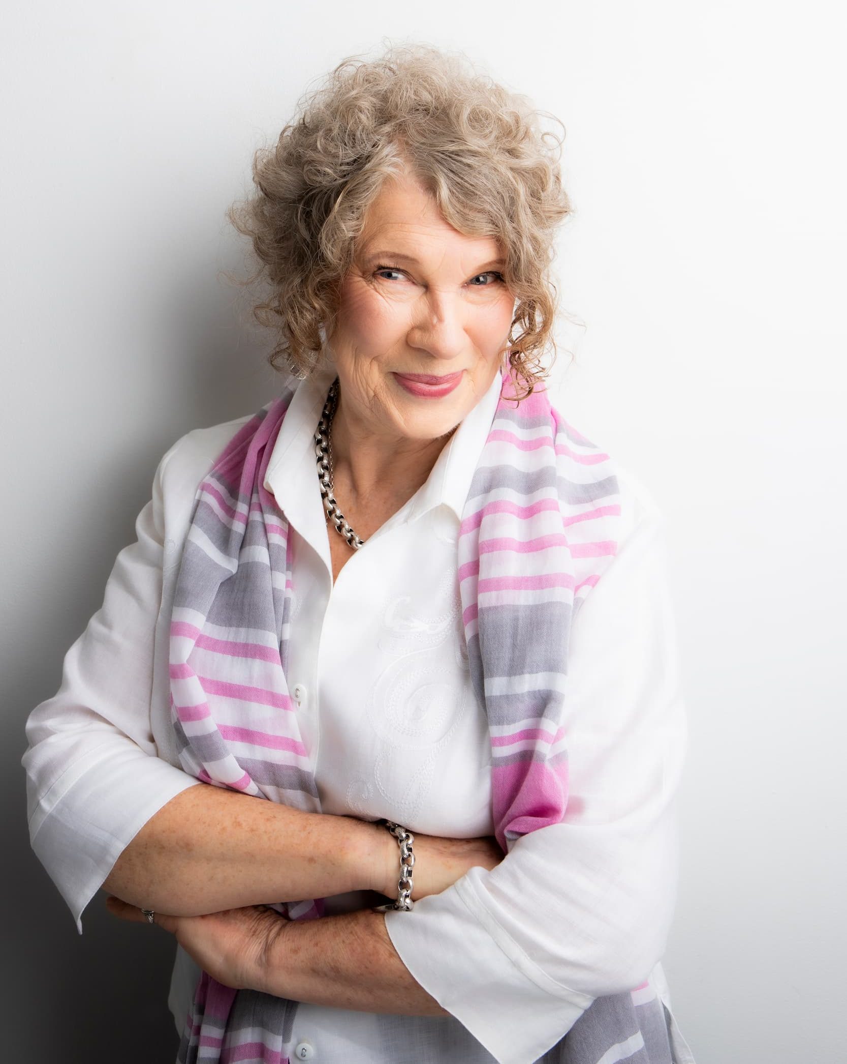 Professional portrait of Narelle Blakeman from Positive Health smiling in a white blouse and pink striped scarf.